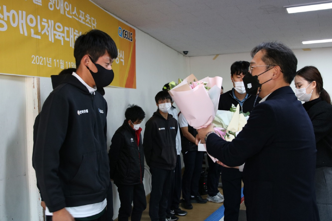 임원배 한화큐셀 전무(오른쪽)가 지난 11일 열린 한화큐셀 장애인체육대회 시상식에서 지적장애인 축구 종목 금메달을 획득한 박재원 한화큐셀 선수에게 꽃다발을 전달하고 있다.[한화큐셀 제공]