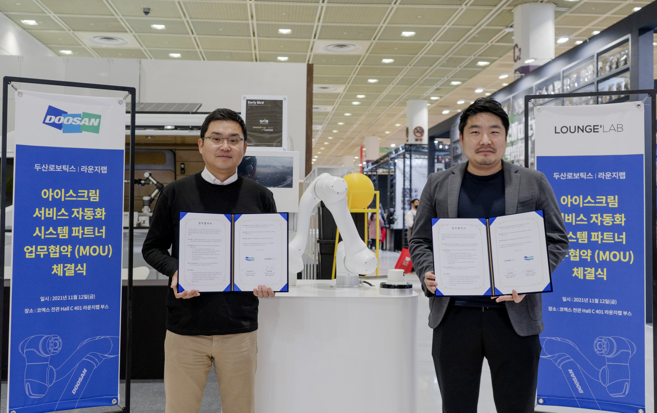 두산로보틱스 류정훈 대표(왼쪽)와 라운지랩 황성재 대표가 지난 12일 서울 삼성동 코엑스 전시장에서 ‘협동로봇 솔루션 활성화 및 아이스크림 서비스 자동화 시스템’을 위한 업무 협약을 체결하고 기념사진을 촬영하고 있다. [두산로보틱스 제공]