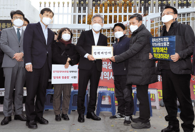 이재명 더불어민주당 대선 후보가 15일 정부서울청사 앞에서 열린 지역화폐·골목상권살리기 운동본부 농성 현장을 방문해 소상공인 자영업자들의 정책제안서를 받고 있다. [국회사진기자단]