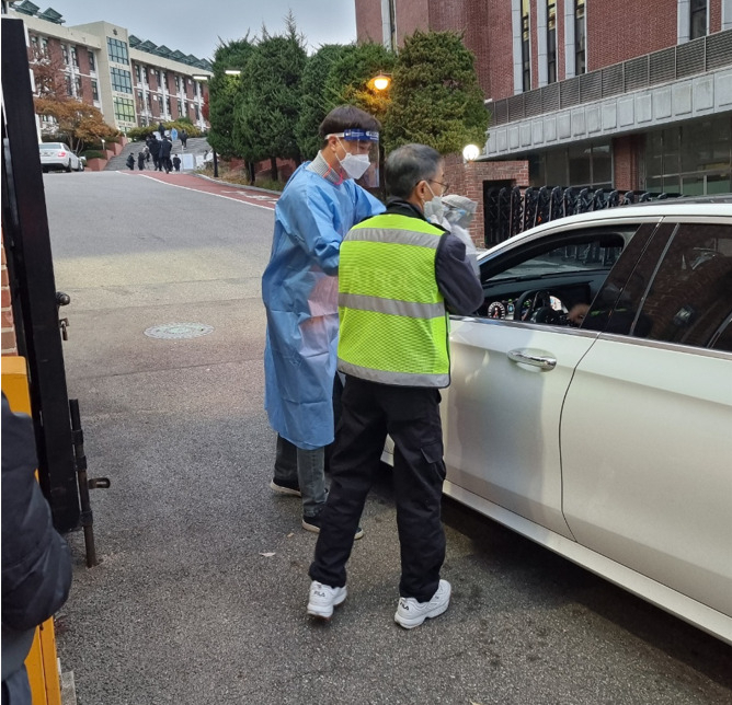 18일 오전 서울 종로구 동성고 정문 앞에서 방역요원이 한 학부모가 학생에게 전달하려 하는 도시락을 대신 받아 전달해주려 하고 있다. 김지헌 기자
