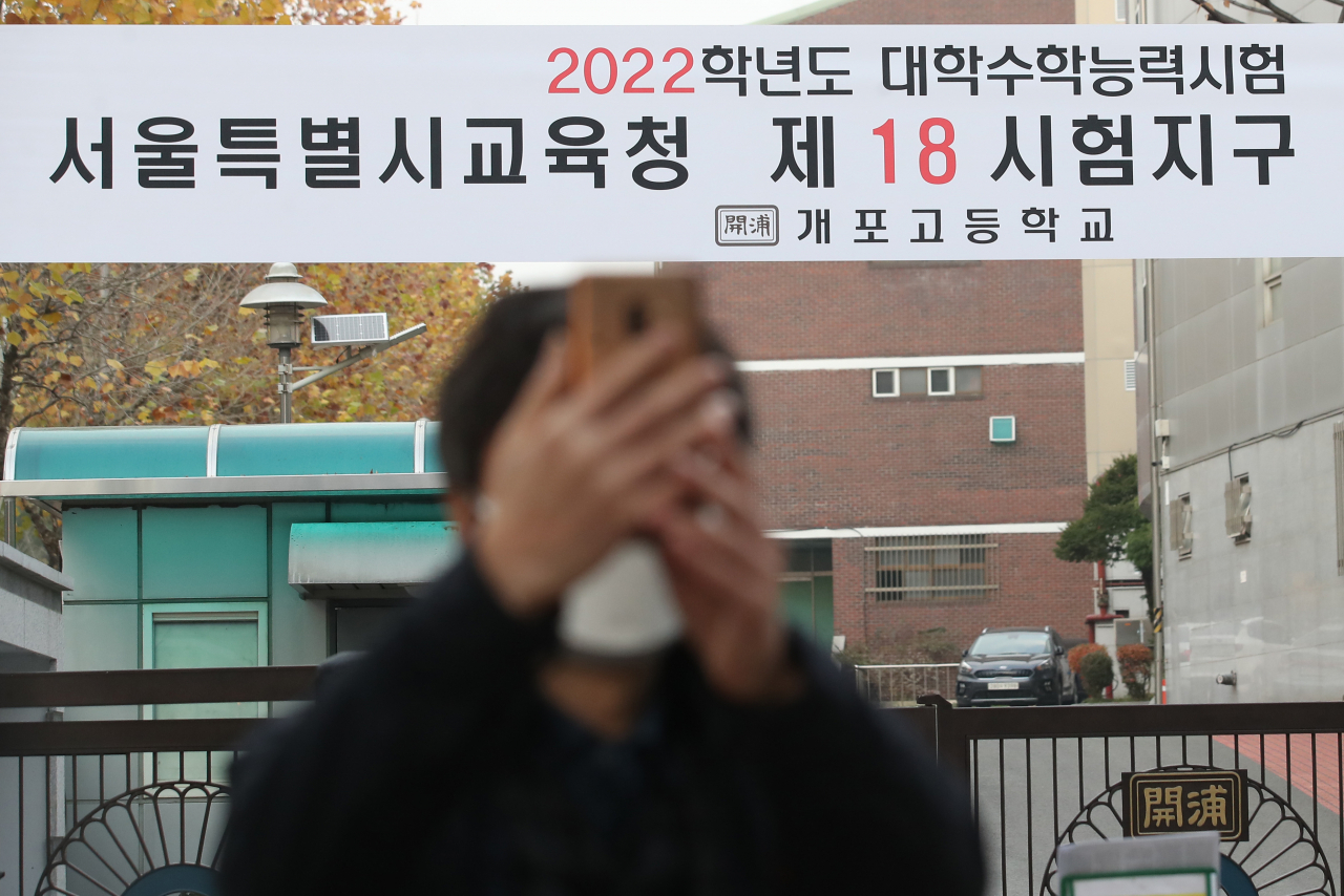 2022학년도 대학수학능력시험일인 18일 오후 서 울 강남구 개포고등학교 앞에서 수험생을 기다리는 학부모가 기념촬영을 하고 있다. [연합]
