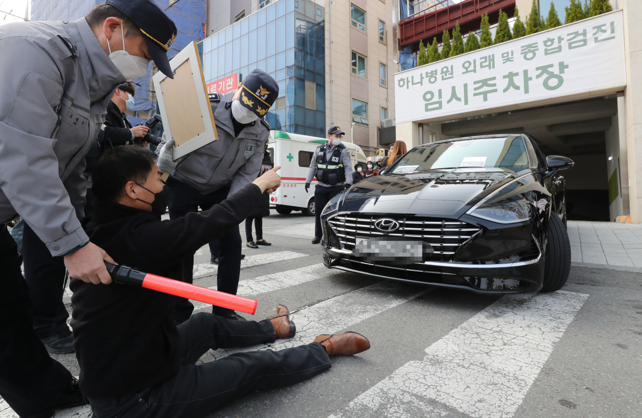 코로나19백신피해자가족협의회(코백회) 회원들이 19일 충북 예방접종 위탁의료기관인 청주시 하나병원 앞에서 정은경 질병관리청장의 차량을 막고 항의하고 있다. [연합]