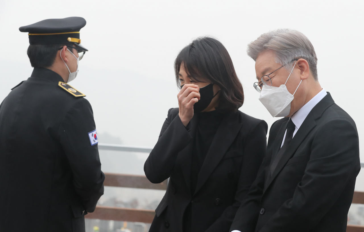 더불어민주당 이재명 대선후보가 연평도 포격전 11주기를 이틀 앞둔 21일 대전시 유성구 국립대전현충원 연평도 포격전 전사자 묘역에서 현충원 관계자로부터 설명을 듣던 중 눈물을 참고 있다. 부인 김혜경 씨는 눈물을 닦고 있다. 연합뉴스