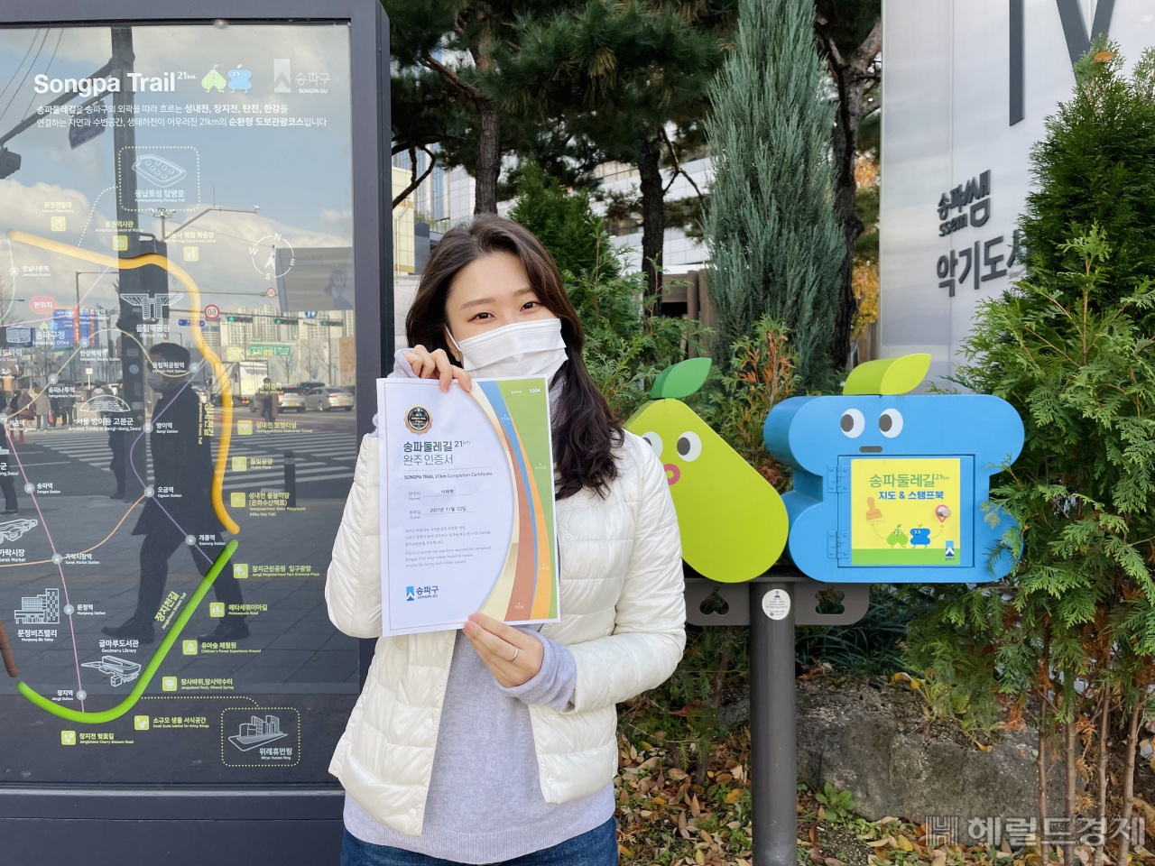 한 시민이 송파둘레길 스템프 투어에 참가해 완주 인증서를 받은 뒤 인증샷을 남기고 있다. [송파구]