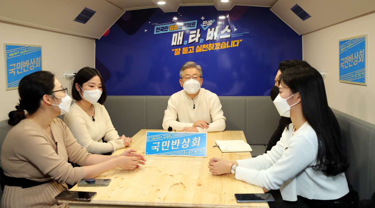 이재명(가운데)더불어민주당 대선후보가 부산·울산·경남 지역 방문 이틀째인 13일 부산시 영도구 부산항에서 부산 청년들과 함께 스튜디오와 좌석이 마련된 매타버스에서 대화를 하고 있다. 매타버스는 '매주 타는 민생버스' 지역 순회 첫 일정으로 부산에서 처음으로 개최했다. [연합]