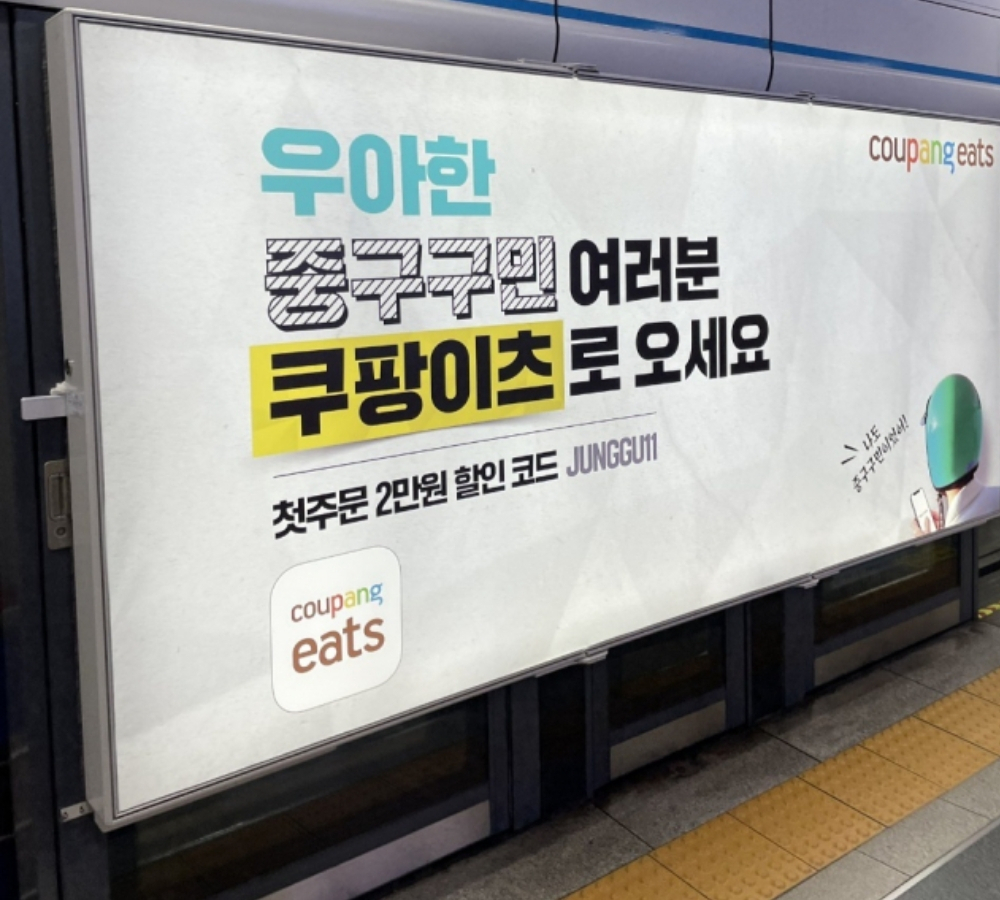 최근 주요 지하철역 플랫폼에 게제된 쿠팡이츠 광고. “우아한 OO구민 여러분 쿠팡이츠로 오세요” 라며 배달의민족 운영사 ‘우아한형제들’을 에둘러 표현하고 있다. [독자 제공]