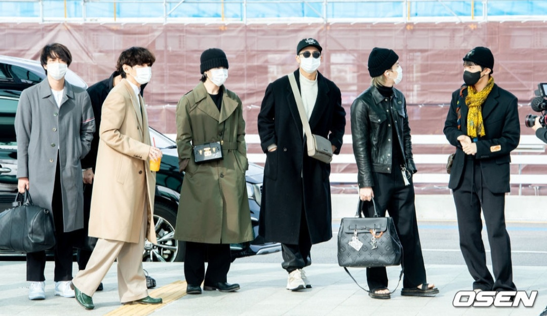 BTS가 지난달 17일 오후 인천국제공항을 통해 LA로 출국하며 선보인 공항패션. 뷔(왼쪽 두 번째)는 베이지 롱코트에 초록 구두를 매치해 눈길을 끌었다. [OSEN]