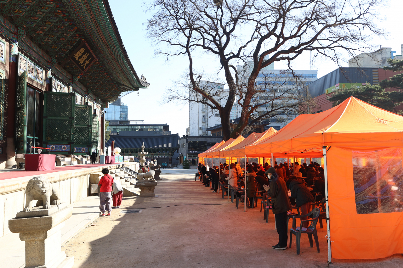 5일 서울 종로구 조계사를 찾은 불교 신자들이 코로나19 확산을 우려해 대웅전 앞 야외 천막에서 기도를 하고 있다. [연합]