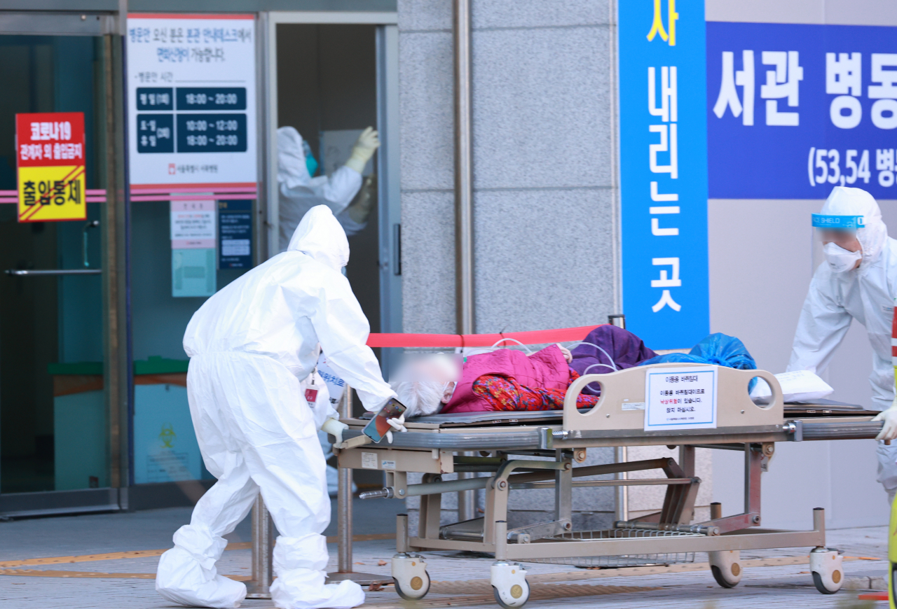 3일 오후 서울 은평구 서울특별시립 서북병원에서 방호복을 입은 의료진이 환자와 함께 병동으로 들어가고 있다. [연합]