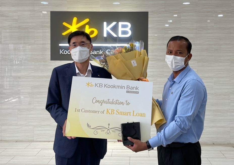 김현종 KB국민은행 캄보디아법인장(사진 왼쪽)이 KB스마트론 1호 고객과 기념촬영을 하고 있다
