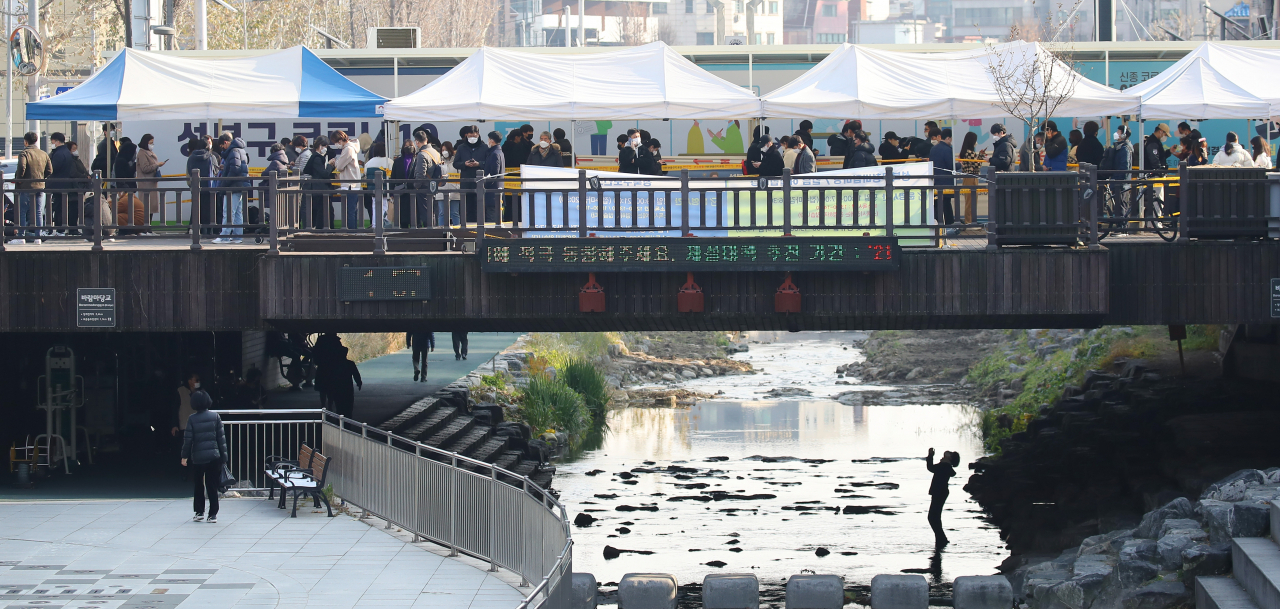 국내 신종 코로나바이러스감염증(코로나19) 신규 확진자수가 7000명을 넘어서며 역대 최다를 기록했다. 서울 성북구청 바람마당 임시선별검사소를 찾은 시민들이 성북천 산책로를 따라 줄지어 서 있다. [연합]
