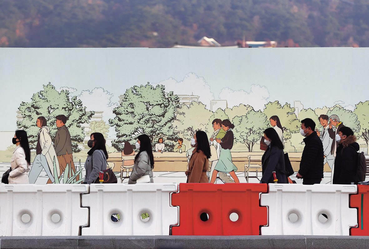 코로나19 확산세가 걷잡을 수 없는 상황으로 치닫고 있는 9일 공사가 진행 중인 서울 광화문광장 차단막 벽화를 배경으로 출근길 시민들이 마스크를 쓴 채 길을 걷고 있다. 비록 이날은 전날보다 확진자수는 소폭 감소했지만 여전히 7000명대를 기록하며 꺾이지 않는 감염 확산세를 보였다. 이대로면 하루 1만명 이상이 코로나19에 확진되는 상황이 곧 올 수 있다는 전망에 힘이 실린다. [연합]