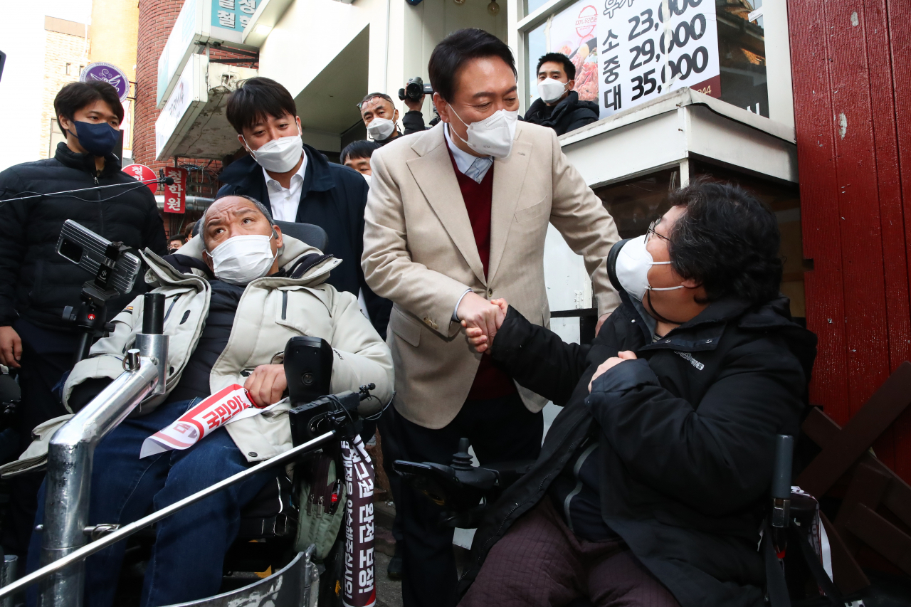 윤석열 국민의힘 대선후보(가운데)와 이준석 대표(왼쪽)가 지난 8일 오후 서울 종로구 대학로 거리 플렛폼74에서 열린 청년문화예술인간담회에 참석하기 전 입구에서 윤 후보와 면담을 요구하던 장애인 단체 회원과 대화하고 있다. [연합]