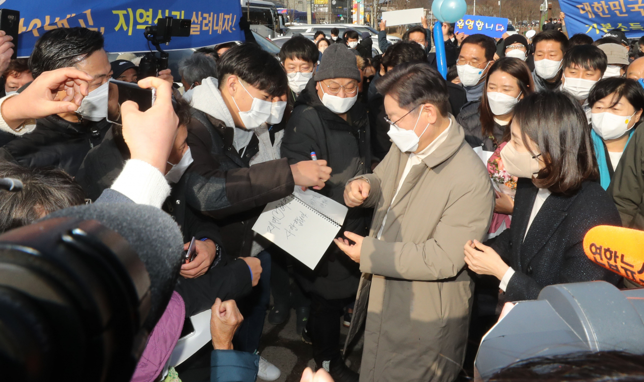 더불어민주당 이재명 대선 후보가 12일 경북 문경시 가은역을 찾아 꼬마열차에 탑승하기에 앞서 지지자들에게 사인을 해주고 있다. [연합]