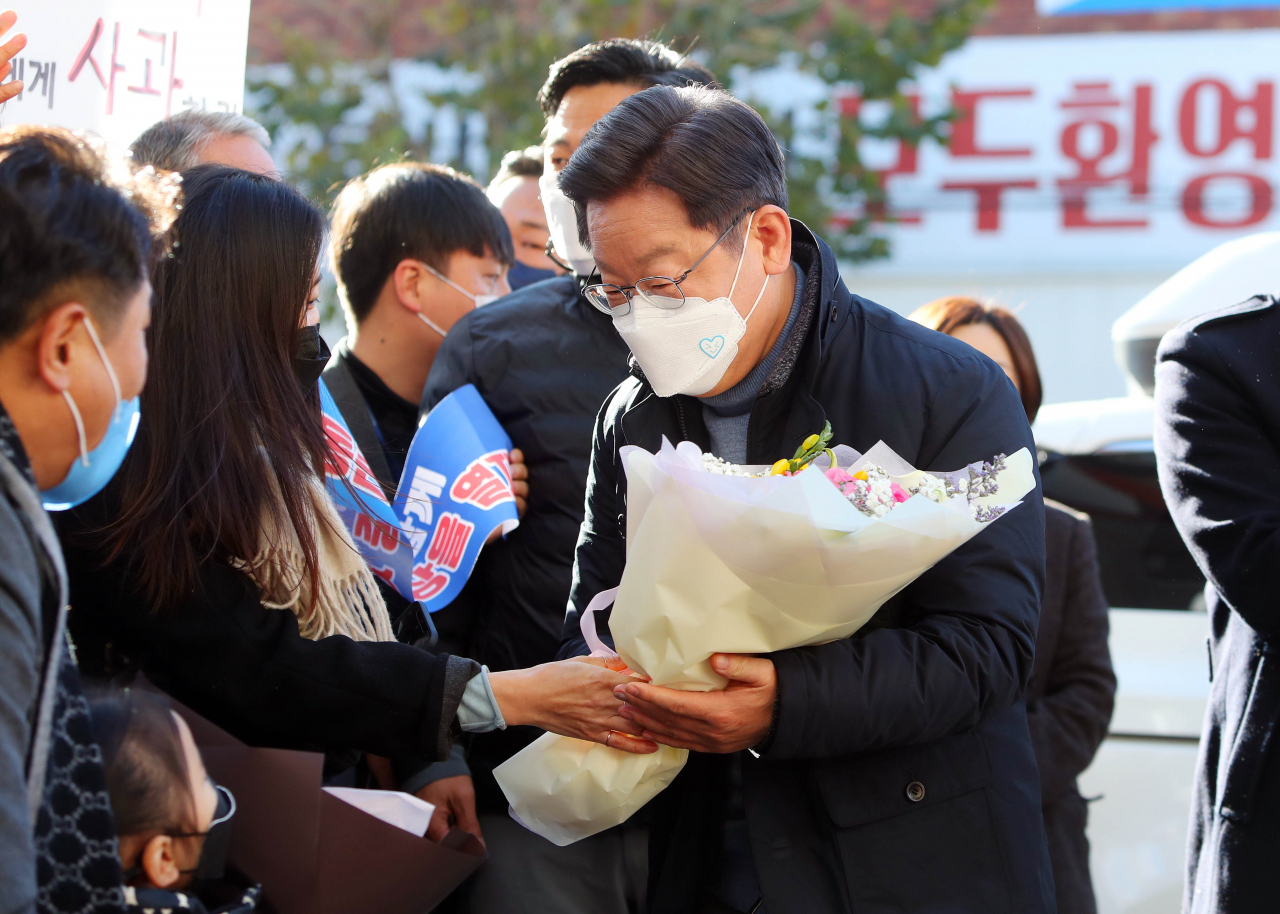 더불어민주당 이재명 대선 후보가 13일 경북 포항시 북구 죽도시장을 찾은 자리에서 지지자에게 꽃다발을 받고 있다. 이 후보는 경북 성주에서 포항으로 이동하는 차량 내에서 독도 경비대원과 영상통화를 진행했다. [연합]