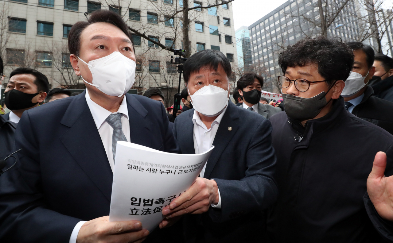 15일 오전 한국노총 간담회를 위해 서울 여의도 한국노총을 찾은 국민의힘 윤석열 대선 후보가 건물 밖에서 기자회견을 하던 한상균 권리찾기유니온 대표(전 민주노총 위원장)를 만나 '근로기준법 개정 촉구 입법청원서'를 전달받고 있다. [연합]