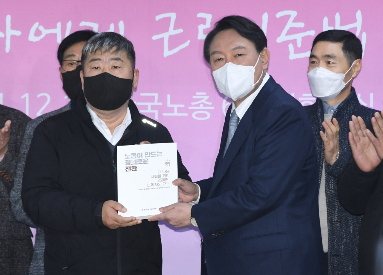 윤석열 국민의힘 대선 후보가 15일 오전 서울 여의도 한국노총에서 정책간담회를 하기 전 김동명 위원장으로부터 노동자의 요구를 담은 책자를 전달받고 있다. 윤 후보는 이 자리에서 공공부문 노동이사제에 대해 ‘찬성’ 입장을 밝혔다. [연합]