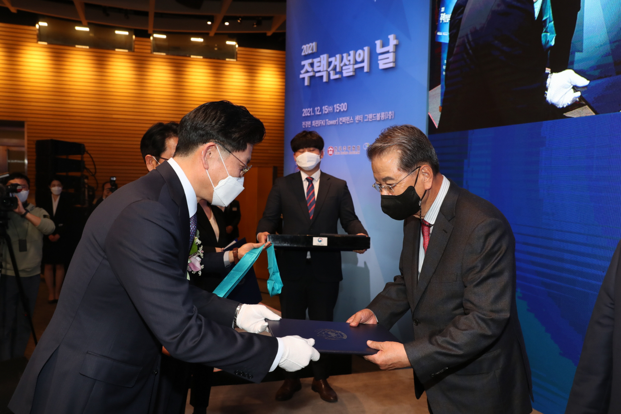 노형욱 국토교통부 장관이 15일 서울 여의도 전경련회관에서 열린 '2021 주택건설의 날' 행사에서 IS아이에스지주 권혁운 대표이사에게 금탑산업 훈장을 수여하고 있다. [대한주택건설협회 제공]