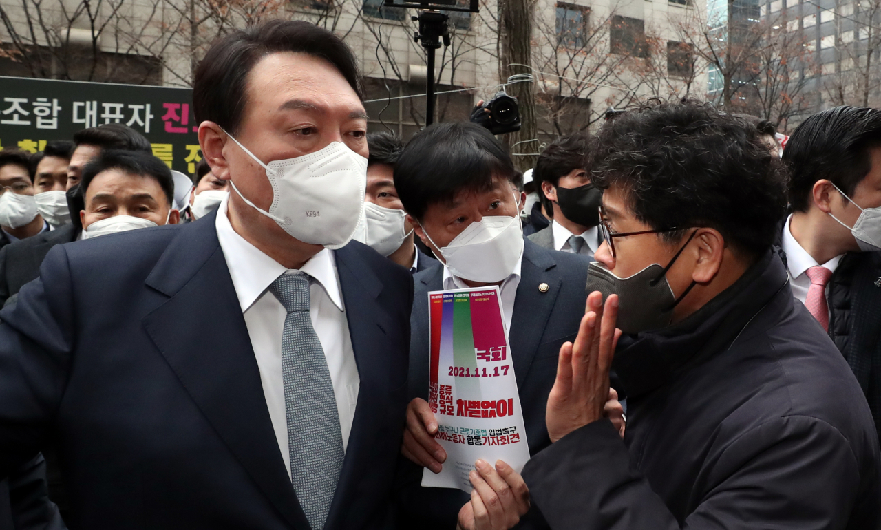15일 오전 한국노총 간담회를 위해 서울 여의도 한국노총을 찾은 국민의힘 윤석열 대선 후보가 건물 밖에서 기자회견을 하던 한상균 권리찾기유니온 대표(전 민주노총 위원장)를 만나 '근로기준법 개정 촉구 입법청원서'를 전달받고 있다. [국회사진기자단]