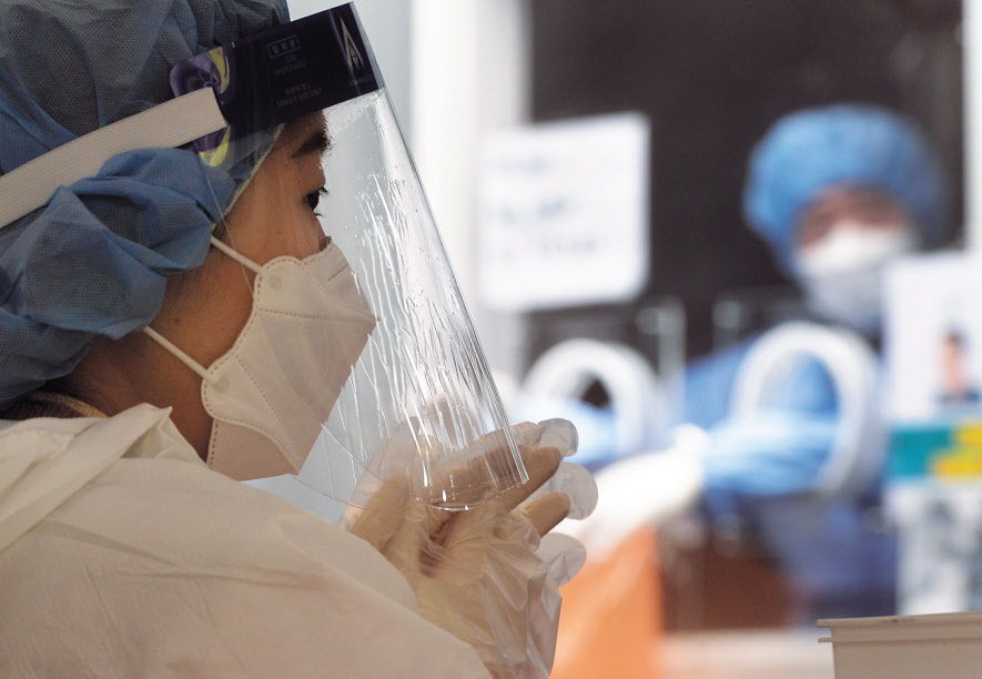 정부가 오는 18일부터 ‘사적 모임 인원 4명·영업 오후 9시 제한’을 골자로 하는 새로운 사회적 거리두기 조정 방안을 16일 발표했다. 위드 코로나(단계적 일상회복)라는 대장정은 채 50일도 못 채우고 다시 강력한 거리두기로 일상이 유턴됐다. 이날 서울 중구 서울역광장 임시선별진료소의 의료진이 코로나19 검사 중 잠시 쉬고 있다. 의료 붕괴의 위기 속 의료진도 지친 기색이 역력하다. 이날 0시 기준 신규 확진자 수는 7622명이다. 박해묵 기자