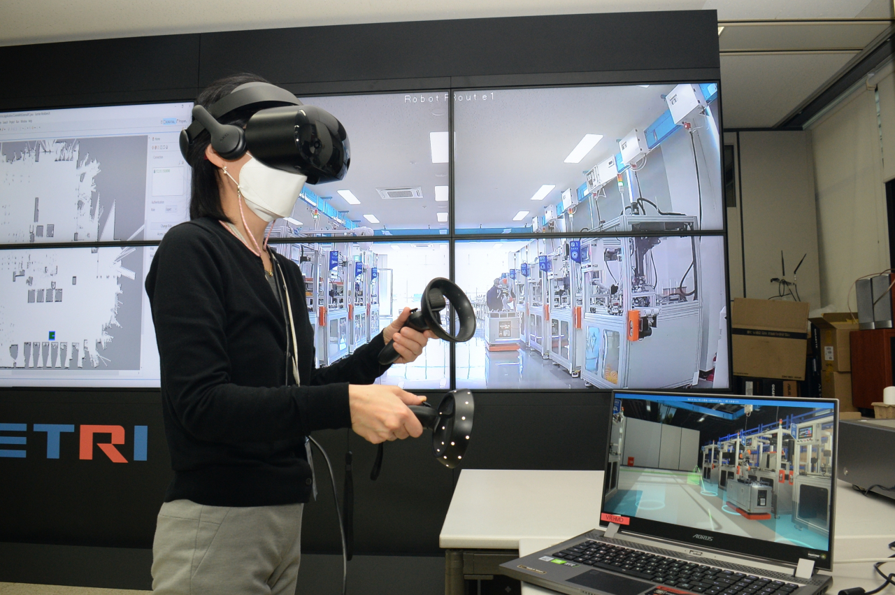 ETRI 연구진이 현장 스마트공장과 로봇 상황과 연동되는 VR 기기로 현장을 점검하고 있는 모습.[ETRI 제공]