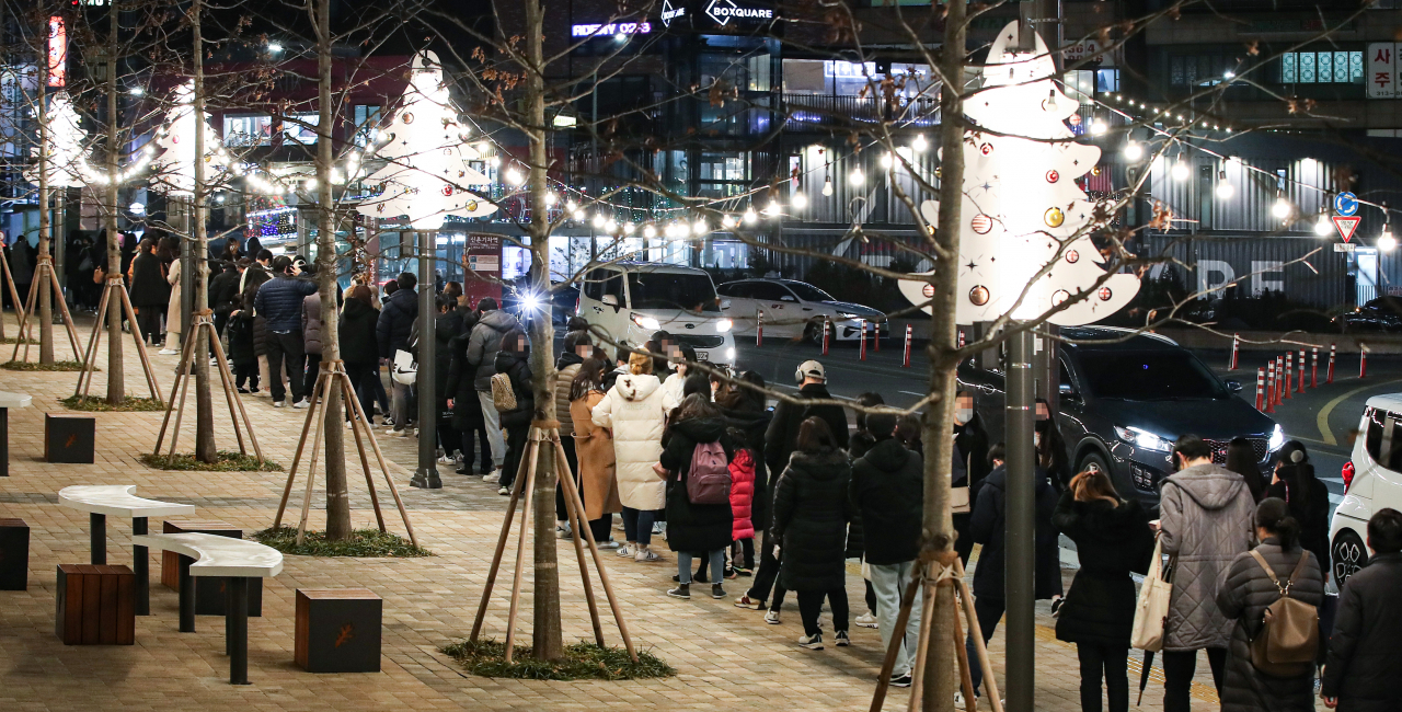 지난 16일 오후 서울 서대문구 신촌역 광장에 마련된 선별진료소를 찾은 시민들이 성탄과 연말을 상징하는 트리 조명 아래 코로나19 검사를 받기 위해 줄지어 서 있다. [연합]