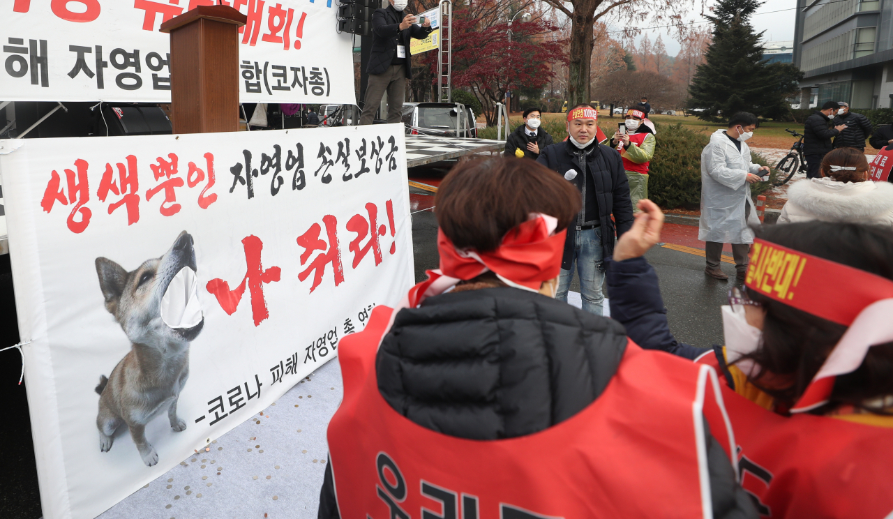 지난 16일 오후 경남 창원시 성산구 경남도청 앞 도청광장 교차로 앞 도로에서 열린 ‘코로나19 피해 실질 보상 촉구 정부·여당 규탄대회’에서 참가자들이 동전을 던지며 손실보상금을 비판하고 있다. [연합]