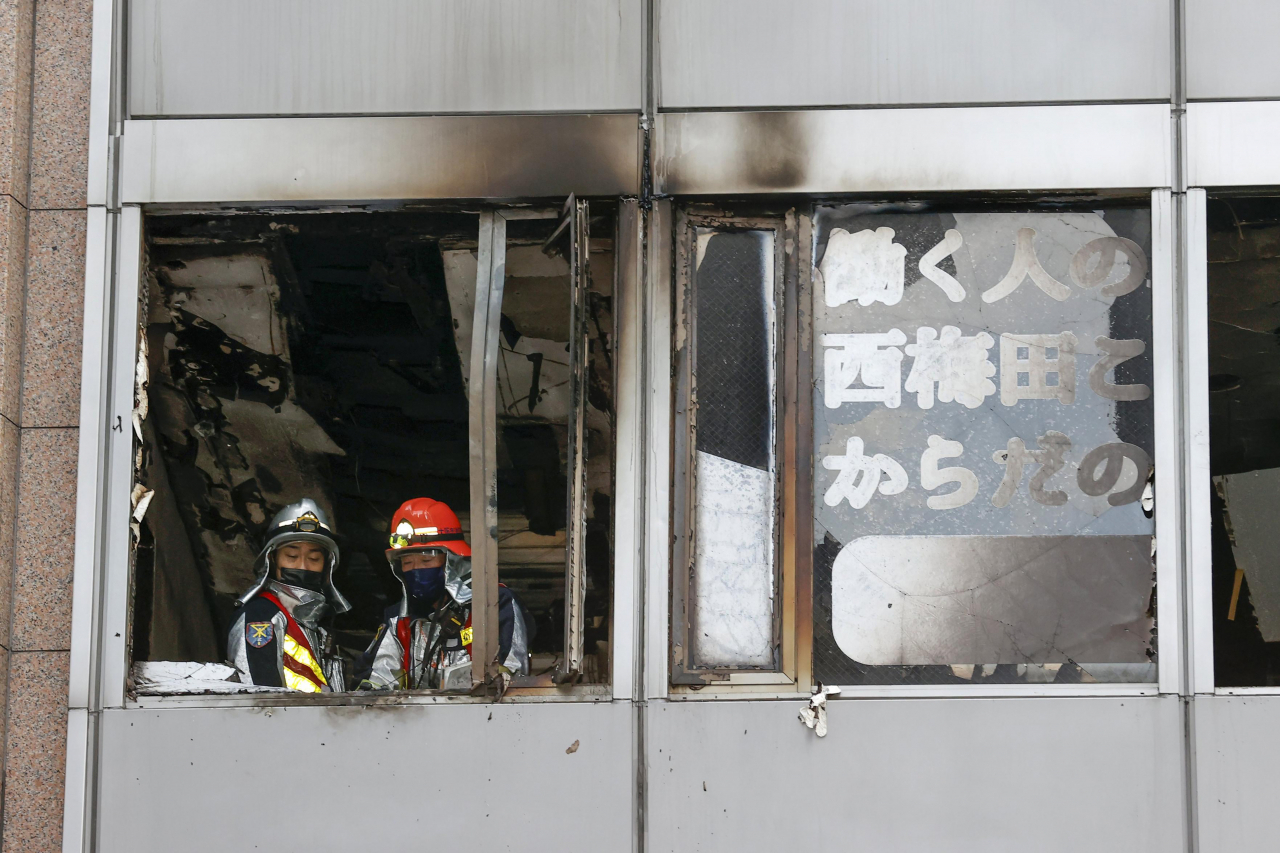 일본 소방관들이 17일 오사카 기타구에서 화재가 난 건물에서 밖을 내려다 보고 있다. [AP]