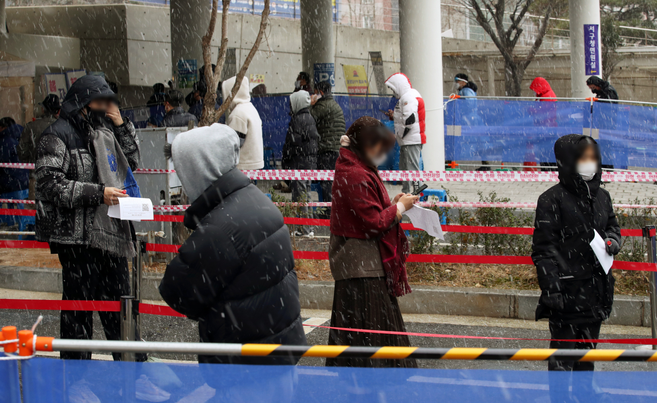 17일 오전 광주 서구보건소 선별진료소에서 신종 코로나바이러스 감염증(코로나19) 검사를 받으려는 시민들이 내리는 눈을 맞으며 줄 서 있다. [연합]