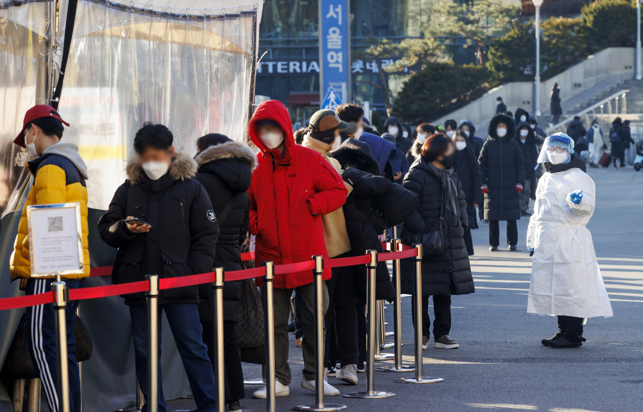 질병관리청에서 관리하는 코로나19 선별검사 시스템 접속에 문제가 생긴 18일 서울역 광장에 마련된 임시 선별검사소에서 관계자가 대기하는 시민들에게 관련 내용을 전달하고 있다. 연합뉴스