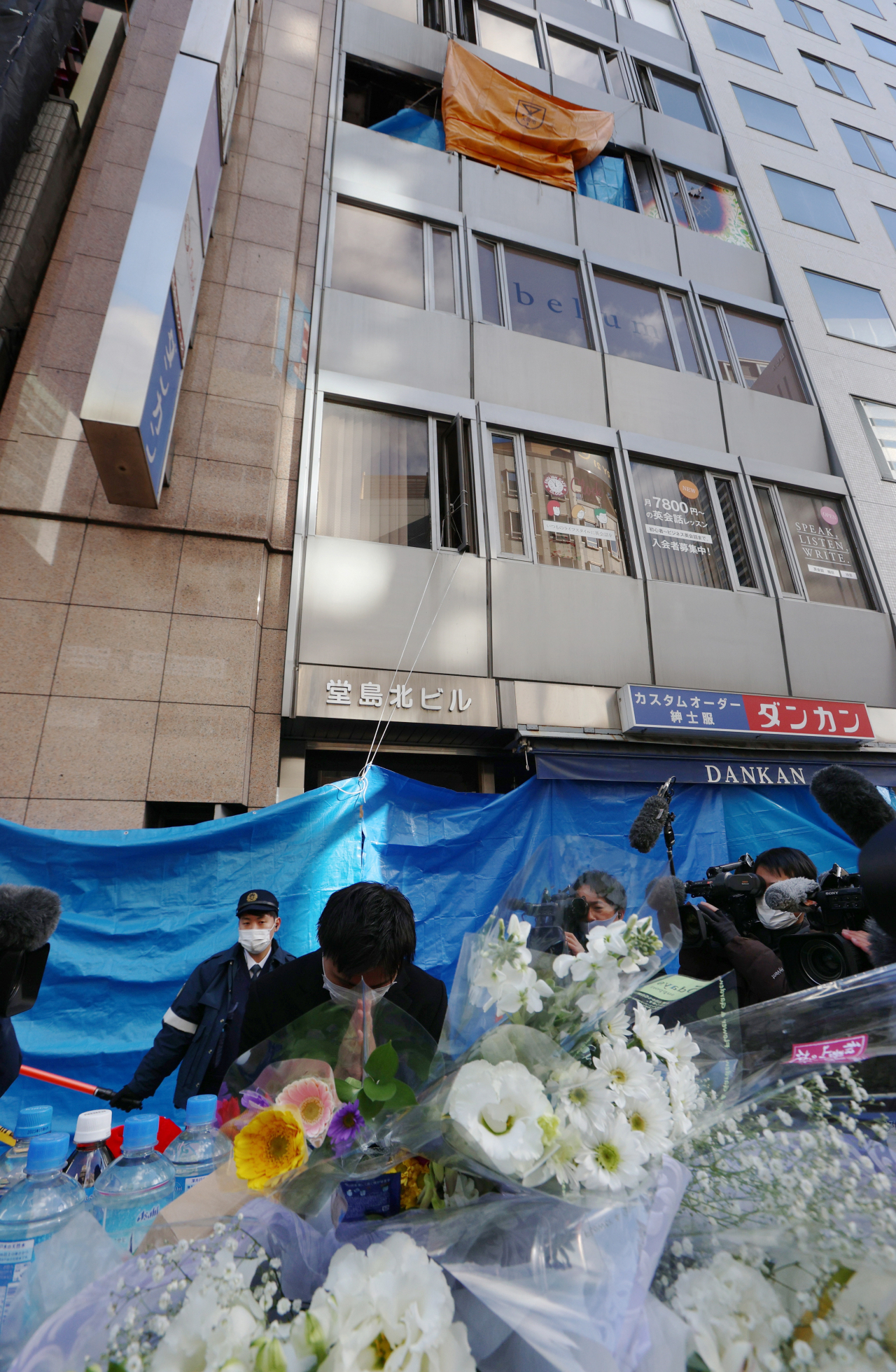 18일(현지시간) 일본 오사카시 기타구 도심서 방화로 인해 24명이 사망한 화재 사건 건물 앞에서 한 시민이 희생자를 기리고 있다. [EPA]
