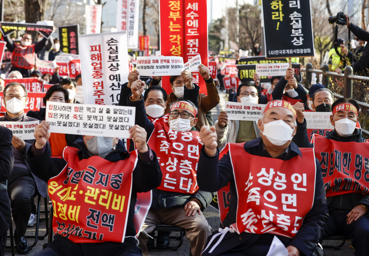 지난 8일 국회 인근에서 열린 ‘코로나 피해 실질 보상 촉구 정부 여당 규탄대회’에서 코로나피해자영업총연합 회원들이 실질적인 손실보상, 집합제한 명령 전면 해제 등을 촉구하는 내용의 손 피켓을 들고 있다. [연합]