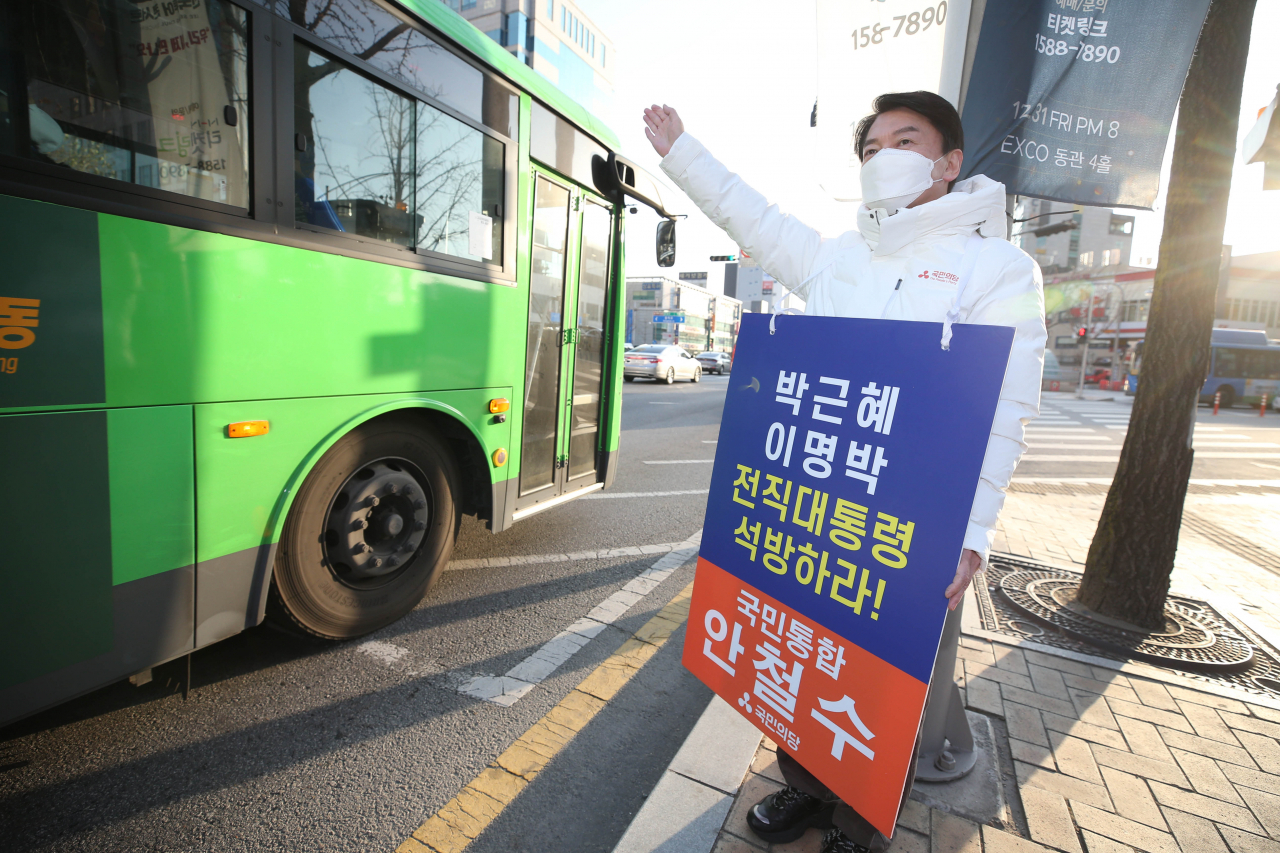 안철수 국민의당 대선 후보가 20일 대구 중구 지하철 2호선 경대병원역 인근에서 이명박·박근혜 전 대통령의 석방을 촉구하는 피켓을 들고 출근길 시민에게 인사하고 있다. [연합]