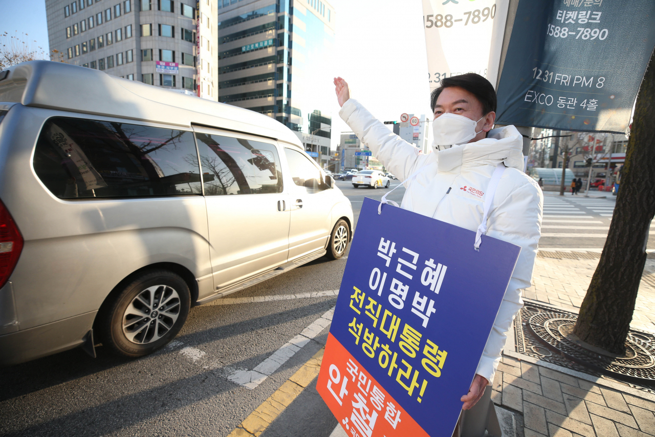 안철수 국민의당 대선후보가 20일 오전 대구 중구 지하철 2호선 경대병원역 인근에서 이명박·박근혜 전 대통령의 석방을 촉구하는 피켓을 들고 출근길 시민에게 인사하고 있다. [연합]