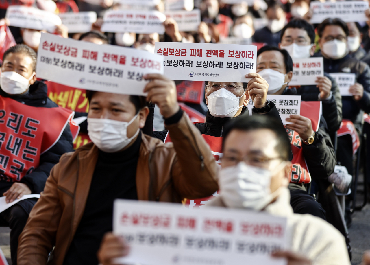 지난 8일 국회 인근에서 열린 ‘코로나 피해 실질 보상 촉구 정부 여당 규탄대회’에서 코로나 피해 자영업 총연합 회원들이 실질적인 손실보상, 집합제한 명령 전면 해제 등을 촉구하는 내용의 손 피켓을 들고 있다. [연합]