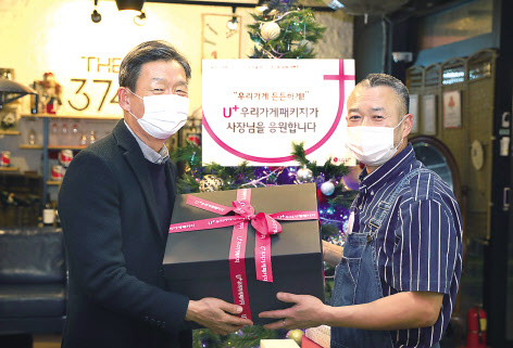 황현식 (왼쪽) LG유플러스 사장이 1차 캠페인을 통해 선정된 서울 강남구 소재 ‘THE 374’를 방문해 소상공인 사장님에게 선물을 증정하고 있다. [LG유플러스 제공]