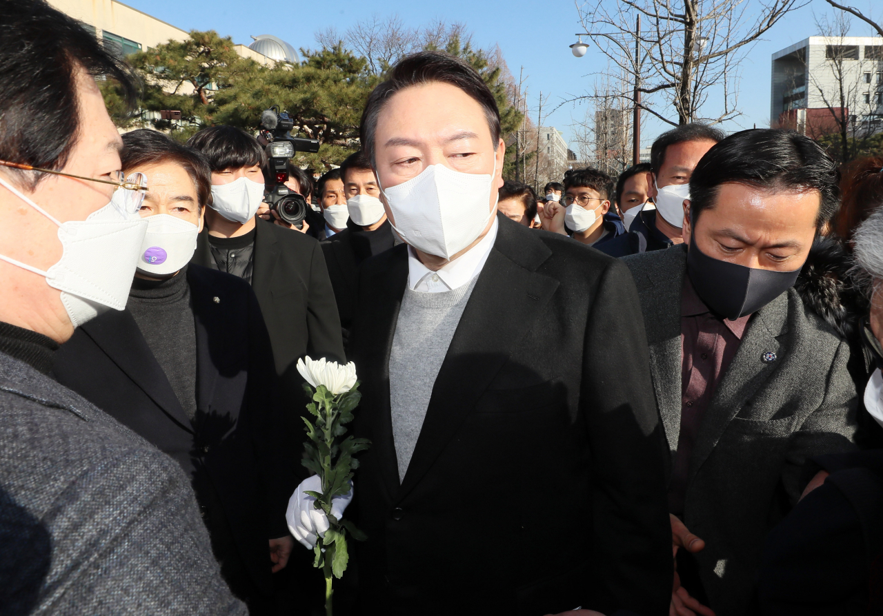 국민의힘 윤석열 대선 후보가 22일 오후 전북 전주시 덕진구 전북대학교 이세종 열사 추모비 앞에서 헌화하려다 이를 반대하는 시민단체의 항의를 받고 발걸음을 돌리고 있다. 윤 후보는 결국 추모비 대신 이세종 열사 표지석에 헌화했다. [연합]