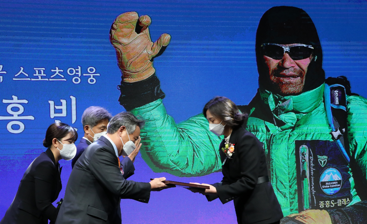 이기흥 대한체육회장이 22일 서울 올림픽공원에서 열린 2021 대한민국 스포츠영웅 헌액식에서 고 김홍빈 대장의 부인 방영은 씨에게 헌액패를 전달하고 있다. [연합]