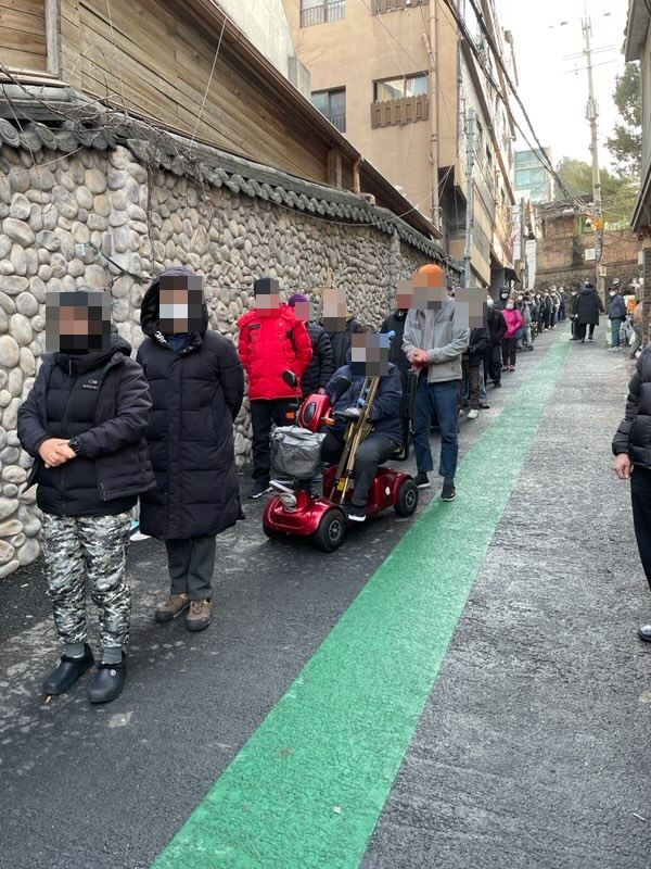 지난 21일 오후 서울 용산구 동자동의 한 거리에서 주민들이 한국교회봉사단에서 실시한 나눔 행사에서 물품을 받기 위해 줄을 서 있다. [한국교회봉사단 제공]