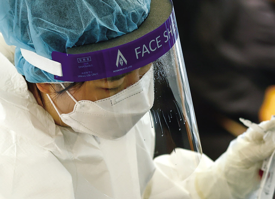 23일 오전 서울역 광장에 마련된 코로나19 임시선별검사소에서 업무중인 의료진의 페이스실드에 입김이 얼어붙어 성에가 끼어 있다. 이날 중앙방역대책본부는 지난 22일 국내 코로나신규 확진자 수가 6919명이라고 밝혔다. 전날보다 신규 확진 규모가 537명 줄었으나 위중증 환자는 1083명, 일일 사망자는 109명이 발생해 둘 다 역대 최다치를 기록했다. 누적 사망자수는 5015명으로 늘었다. [연합]