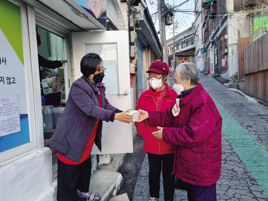 지난 21일 오후 서울 용산구 동자동 엘림교회 앞에서 이 교회 윤정순(왼쪽) 목사가 한 주민에게 순댓국을 나눠주고 있다. 김영철 기자