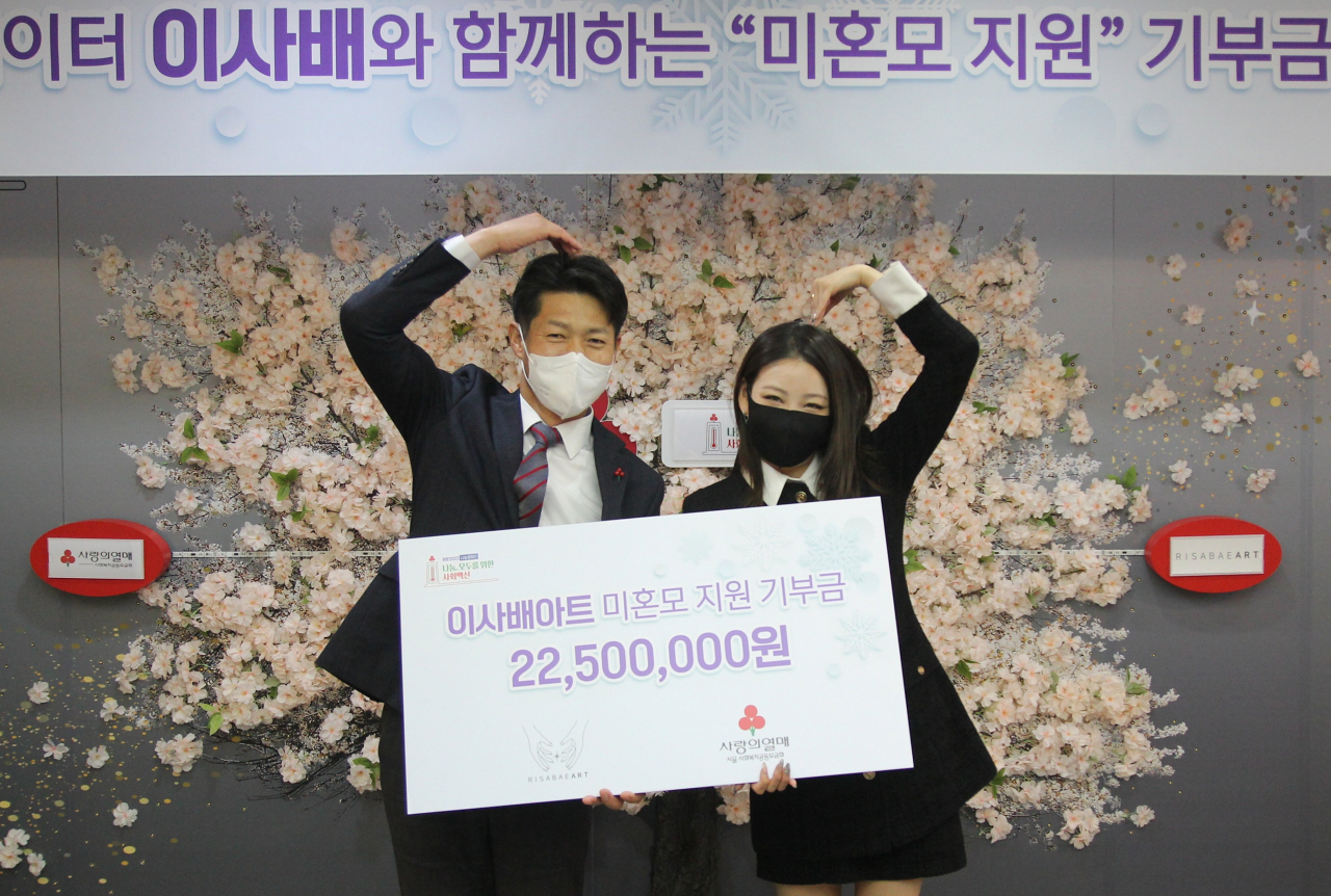 이사배의 기부금 전달식. 김진곤 서울사랑의 열매 사무처장이 세상 즐거운 표정으로, 이사배 아티스트와 팔 하트를 그려보이고 있다.