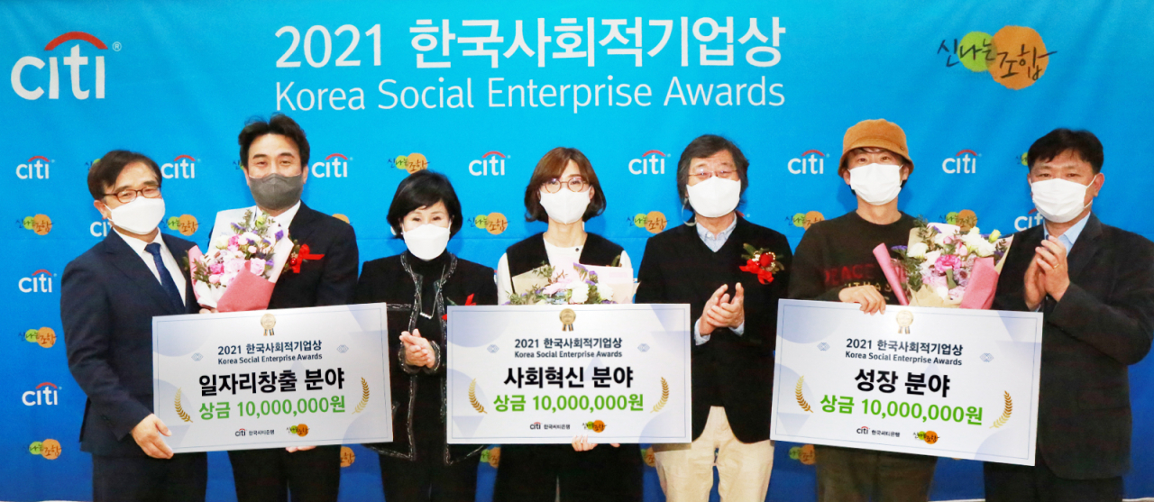 한국씨티은행은 신나는조합과 23일 오후 서울 영등포구 소재 소셜캠퍼스온에서 ‘2021 한국사회적기업상’ 시상식을 개최했다. 유명순 한국씨티은행장(왼쪽 세번째)과 이선우 신나는조합 이사장(오른쪽 세번째) 및 정현곤 한국사회적기업진흥원장(왼쪽 첫번째)이 수상기업 대표들과 함께 기념사진을 촬영하고 있다.[한국씨티은행 제공]