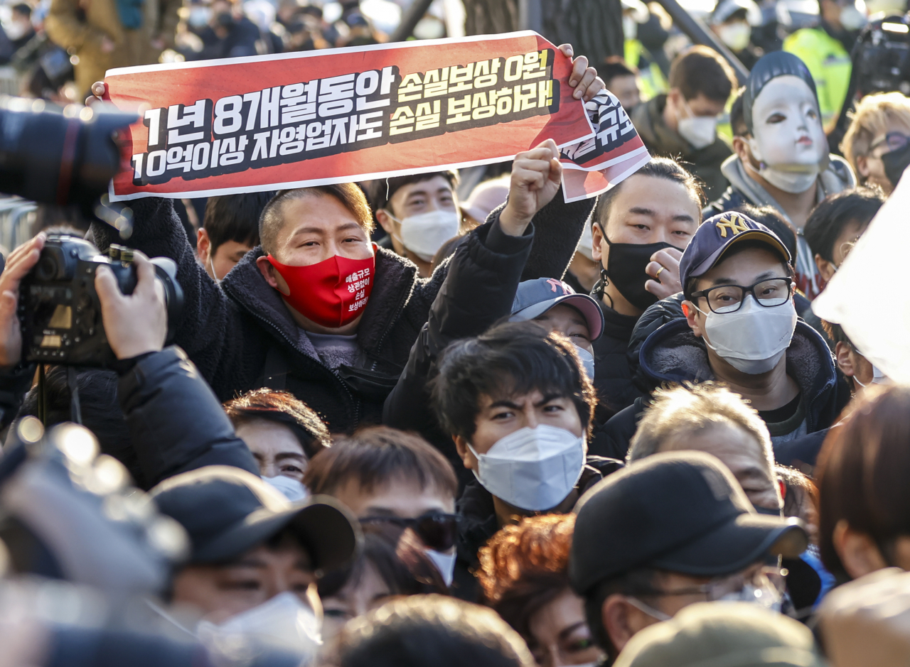 [사진=22일 오후 서울 광화문시민열린마당에서 열린 '코로나19 대응 전국자영업자비상대책위원회(자영업비대위) 정부 방역대책 반대 총궐기 대회'에서 인원 제한으로 집회 현장에 들어오지 못한 회원들이 펜스 밖에서 구호를 외치고 있다.][연합]