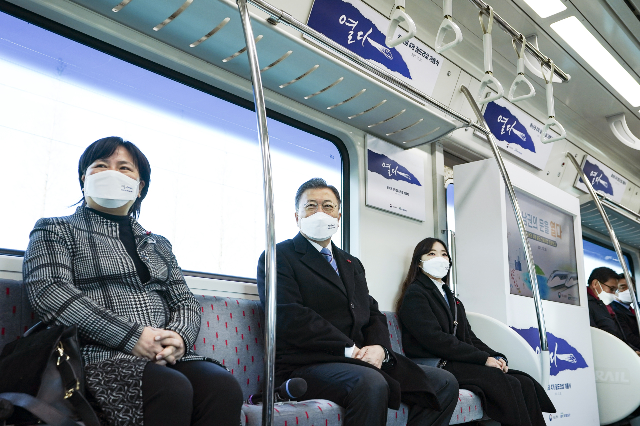 President Moon Jae-in (center) sits in a subway train traveling from Ulsan to Busan as part of attending an event held Tuesday to celebrate the opening of 142.2 kilometers of new subway lines spanning across southeastern parts of the country. (Yonhap)
