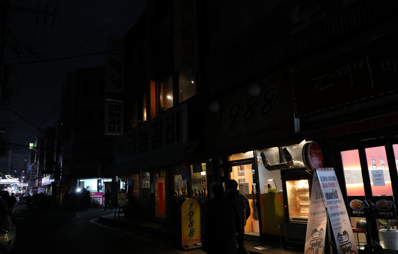 지난 28일 처녁 서울 강북구 수유리먹자골목 상인들이 신종 코로나바이러스 감염증(코로나19) 방역정책에 항의하는 의미로 간판의 불을 끄고 영업하고 있다. 같은 날 한국외식업중앙회 등 소상공인단체로 구성된 코로나피해자영업총연합(코자총)은 정부의 코로나19 방역정책에 반발해 소등시위를 벌였다. [연합]