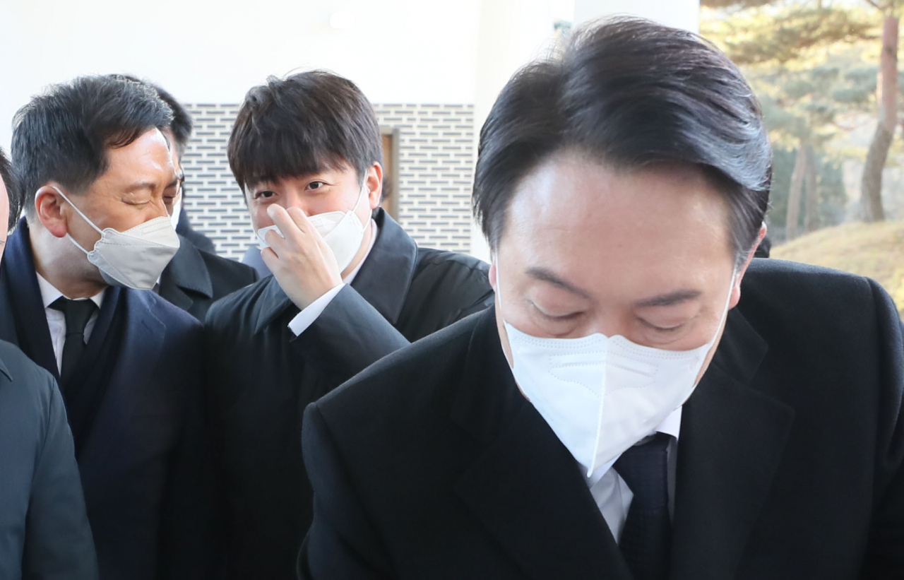 윤석열 국민의힘 대선후보가 1일 오전 서울 동작구 국립서울현충원을 참배한 뒤 방명록을 작성하고 있다. 윤 후보 뒤로 김기현 원내대표와 대화하는 이준석 대표가 보인다. [연합]