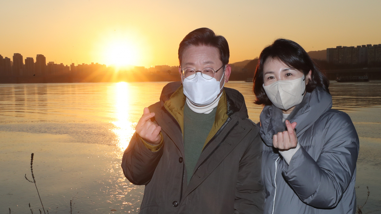 더불어민주당 이재명 대선 후보와 부인 김혜경 씨가 새해 첫날인 1일 오전 서울 용산구 노들섬에서 열린 '2022 글로벌 해돋이 : 지구 한 바퀴' 온라인 해맞이 행사 뒤 떠오르는 해를 배경으로 기념사진을 찍고 있다. 연합뉴스