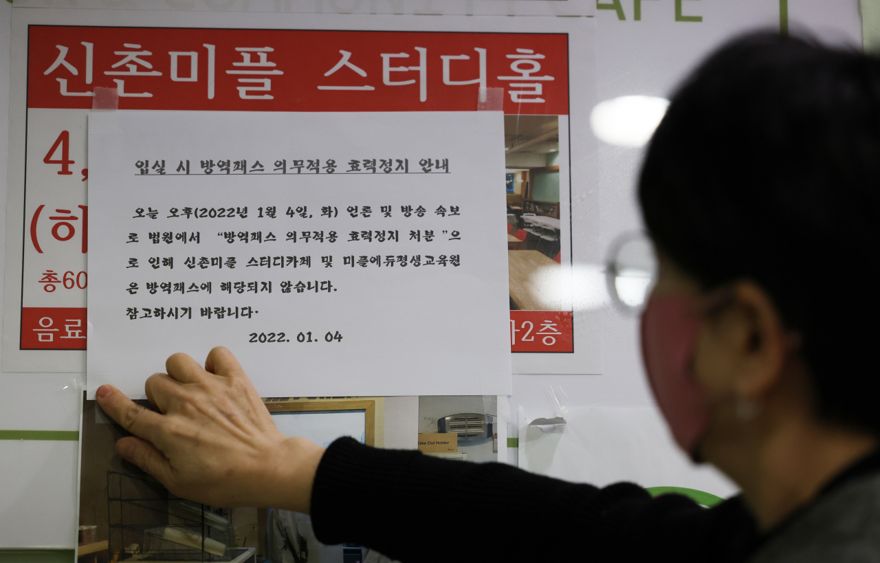 4일 오후 서울 서대문구 신촌 한 스터디카페에서 관계자가 ‘방역패스 적용 중단’ 안내문을 붙이고 있다. 이날 서울행정법원 행정8부(부장 이종환)는 4일 함께하는사교육연합·전국학부모단체연합 등이 보건복지부 장관을 상대로 낸 집행정지(효력정지) 신청을 일부 받아들였다. [연합]