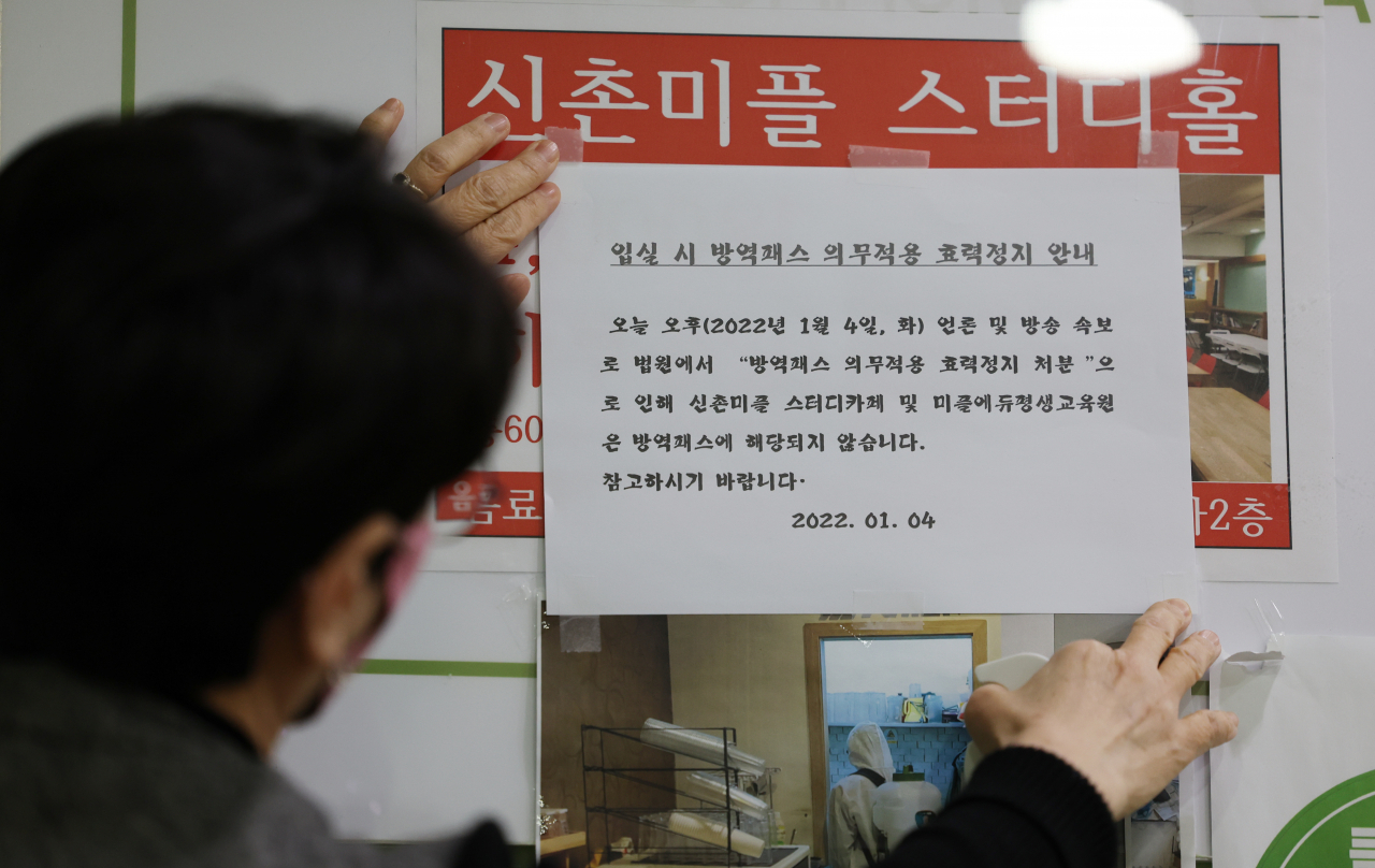 4일 오후 서울 서대문구 신촌 한 스터디카페에서 관계자가 '방역패스 적용 중단' 안내문을 붙이고 있다. 이날 서울행정법원 행정8부(이종환 부장판사)는 4일 함께하는사교육연합·전국학부모단체연합 등이 보건복지부 장관을 상대로 낸 집행정지(효력정지) 신청을 일부 받아들였다. [연합]